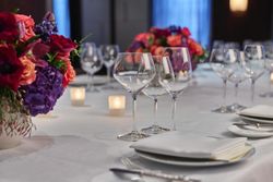 Elegant table setting with wine glasses, white napkins, and floral centerpieces at fine dining restaurant Daniel.