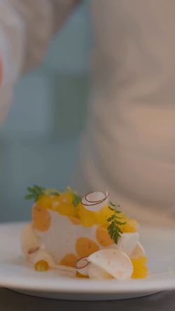 Delicate plated dessert garnished with herbs and thinly sliced fruit at Daniel fine dining restaurant.