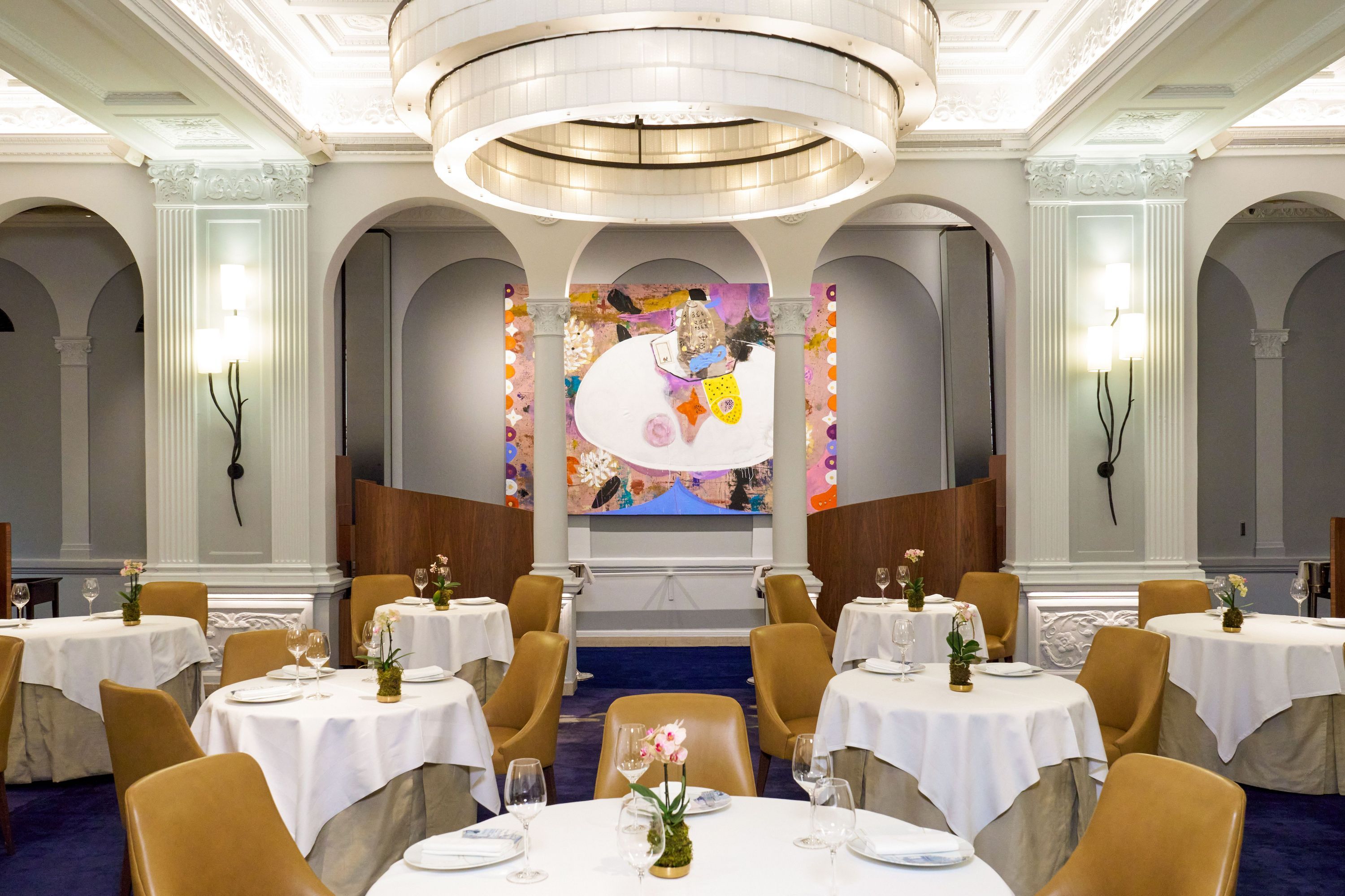 Fine dining restaurant Daniel with white tablecloths, soft lighting, modern art, and elegant décor in an ornate room.
