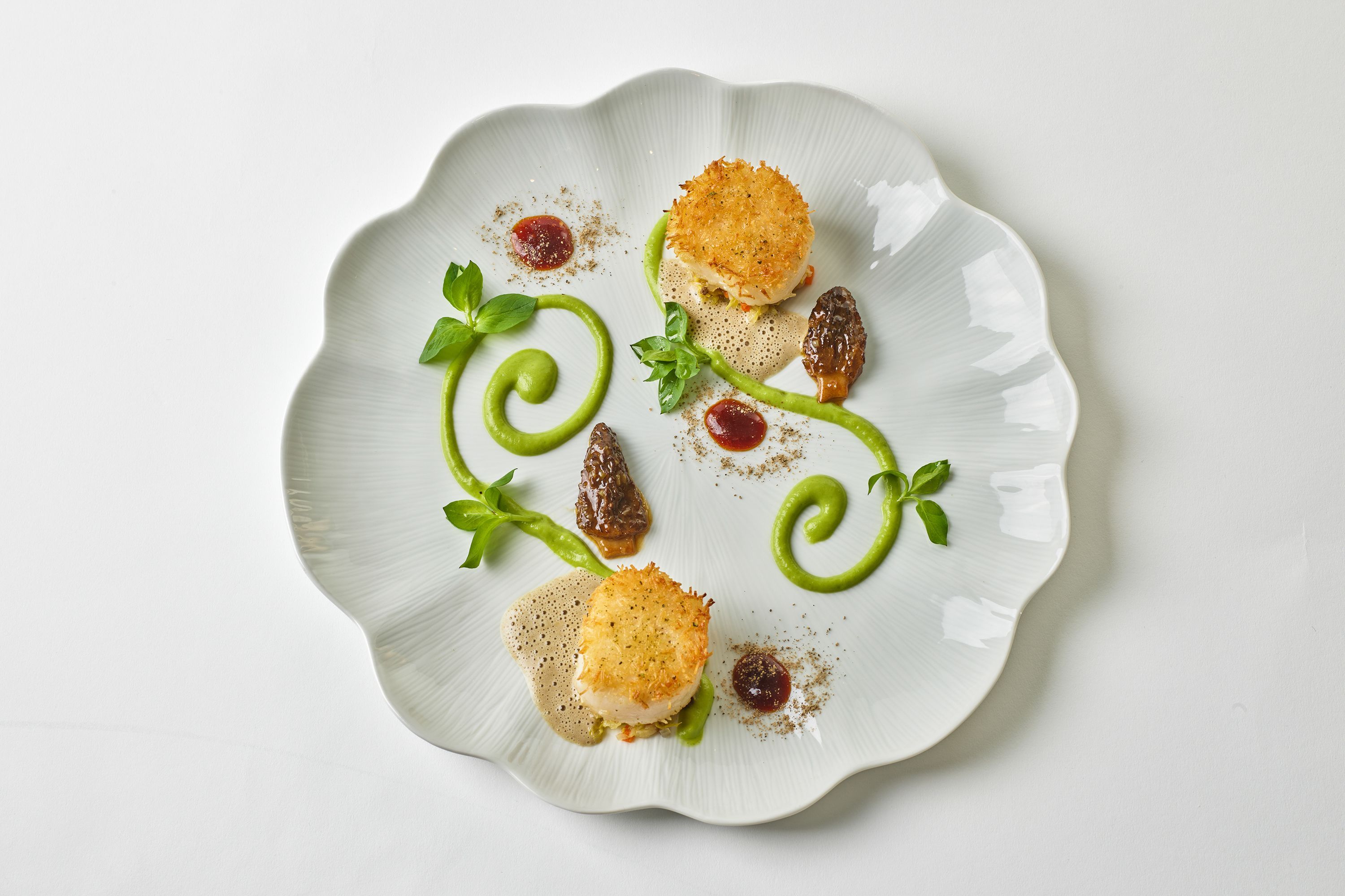 Gourmet dish featuring breaded fish, morel mushrooms, and green puree on an elegant white plate.
