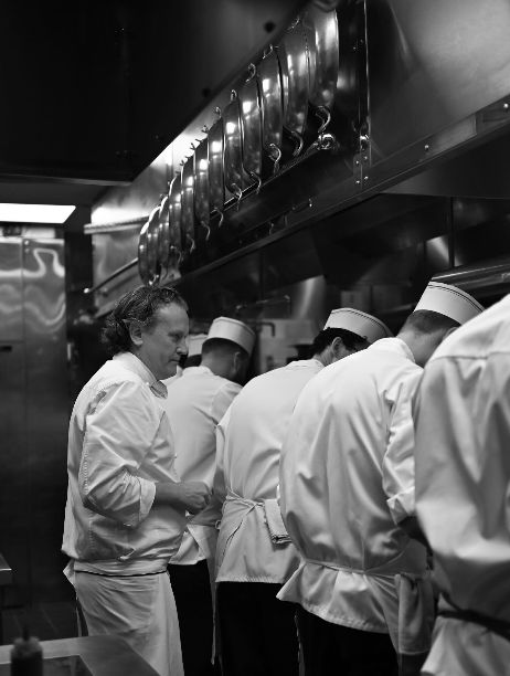 A kitchen scene at Daniel, showcasing chefs in white uniforms preparing meals in a fine dining setting.